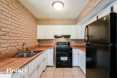 A kitchen with a black refrigerator and white cabinets.