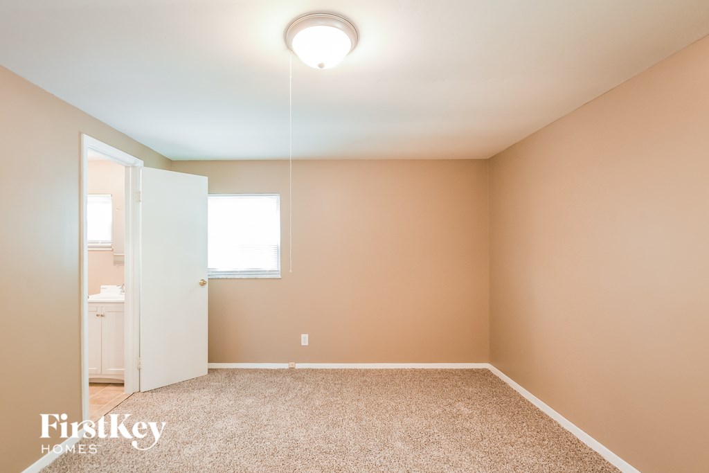 A carpeted room with a light on the ceiling and a doorway leading to another room.