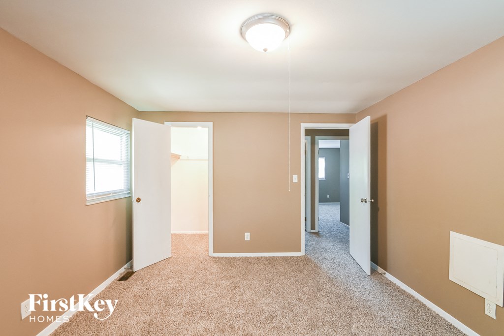 A room with a carpet floor and a FirstKey HOMES logo.