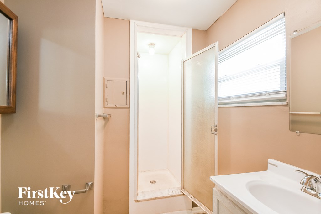 A bathroom with a sink, mirror, and shower.