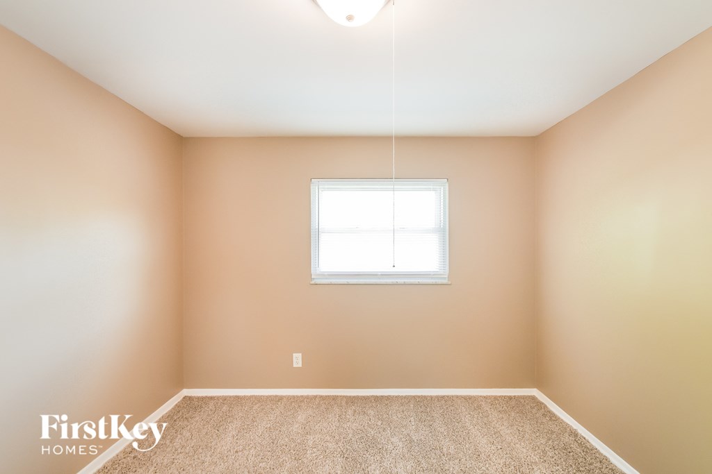 A room with a window and a carpeted floor.