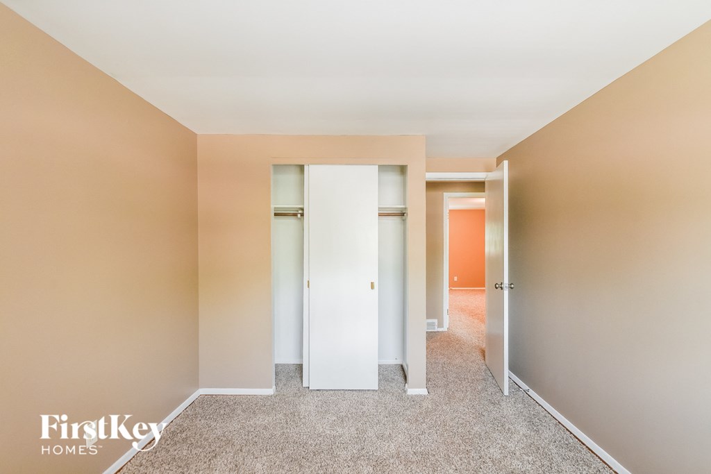 A hallway with a white door and carpeted floor.