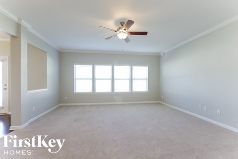 a empty living room with a ceiling fan and a window