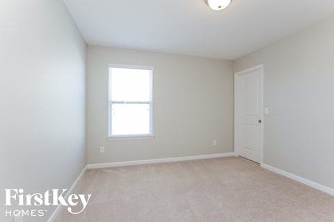 a bedroom with white walls and a window and a white door