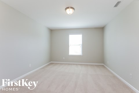 a spacious room with white walls and a window