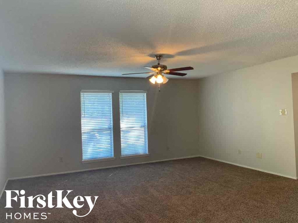 an empty living room with a ceiling fan and a window