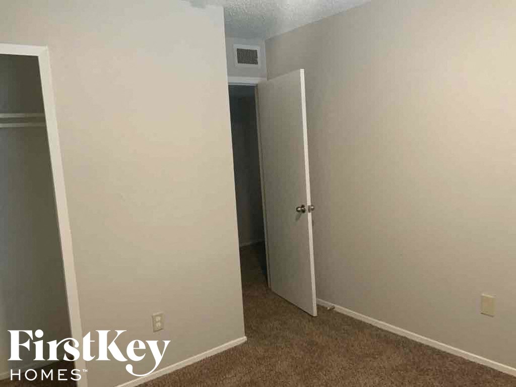 an empty room with a door open to a closet
