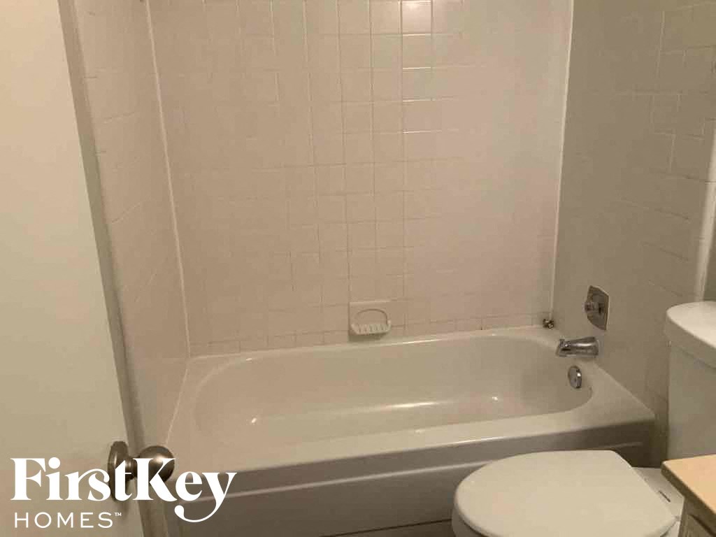 a white bath tub in a white bathroom with a toilet