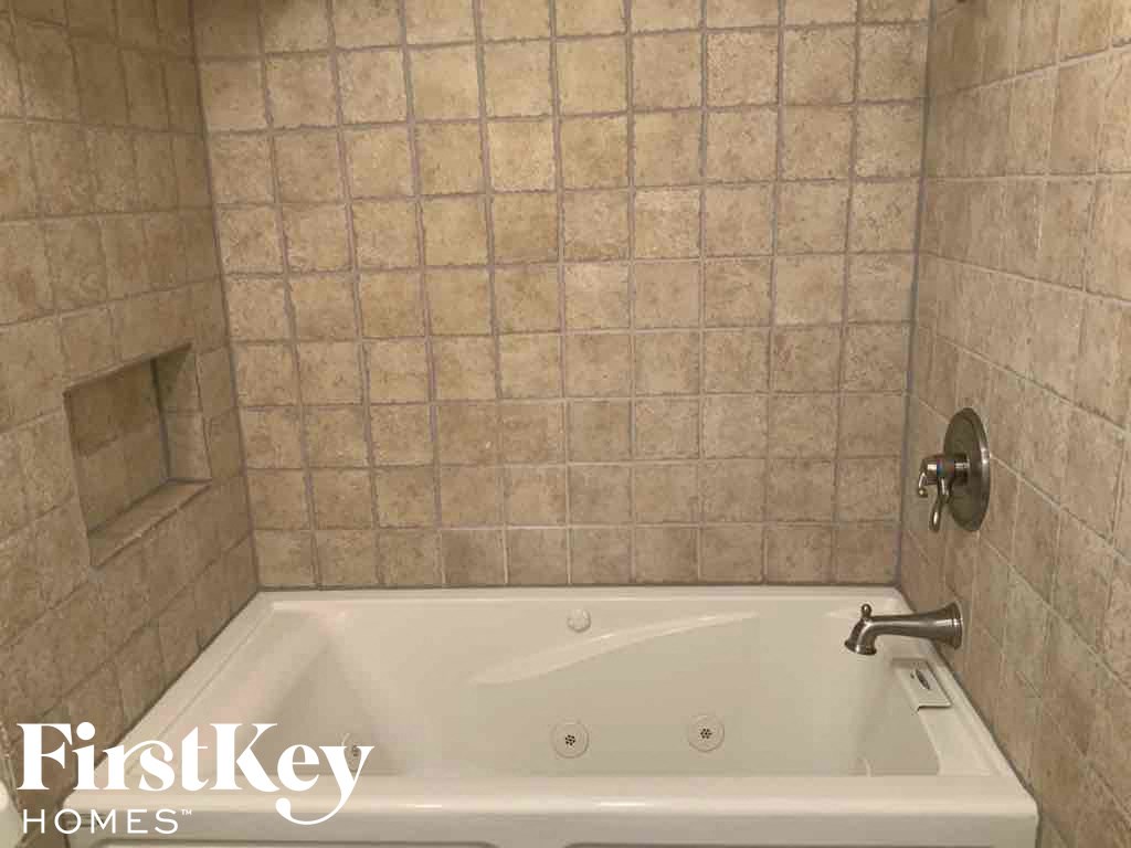 a small bathroom with a tub and a tiled wall