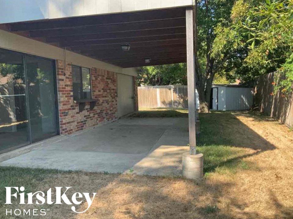 a backyard with a concrete patio and a brick house