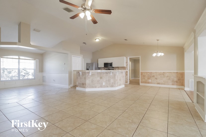 A spacious living room with a fan and tiled flooring.