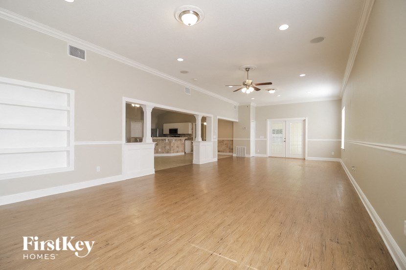 A spacious room with wooden floors and a ceiling fan.