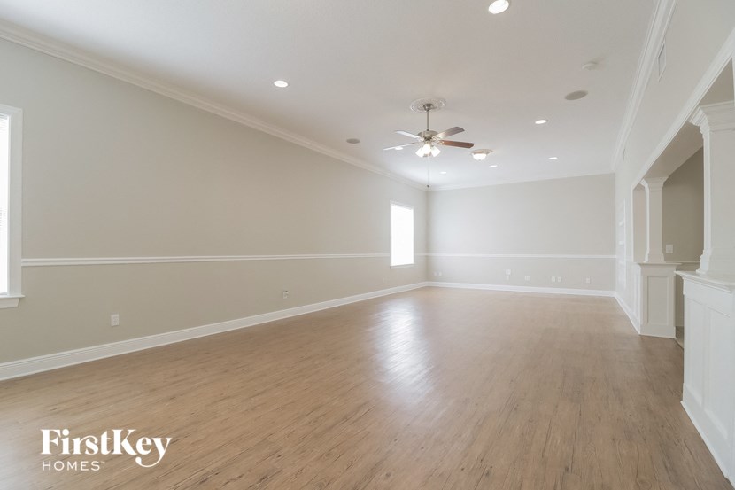 A spacious room with wooden floors and a ceiling fan.