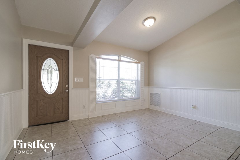 A room with a wooden door and a window with white blinds.
