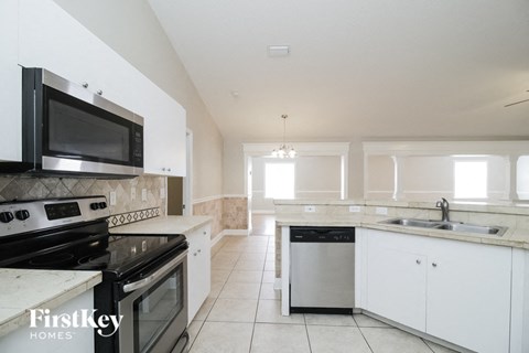 A kitchen with white cabinets and black appliances.