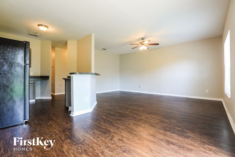 an empty living room with wood flooring and a ceiling fan