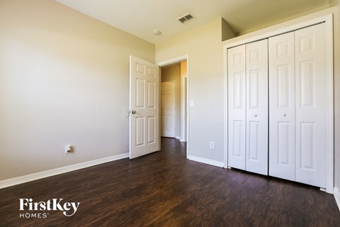 a bedroom with white closets and wood flooring and a door to a hallway