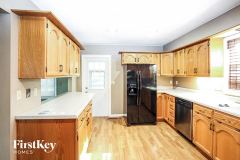 A kitchen with wooden cabinets and a black fridge.