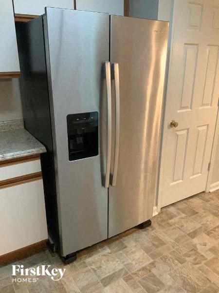 A stainless steel refrigerator with a black door is in a kitchen.