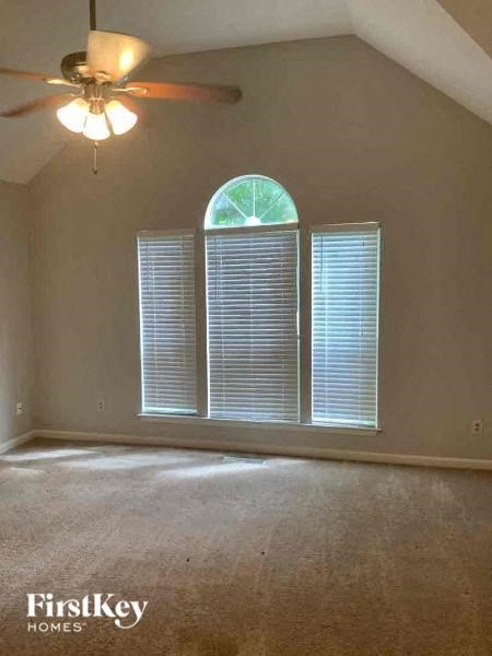 A room with a ceiling fan and a window with blinds.