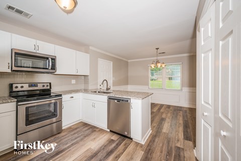 A kitchen with white cabinets and a wooden floor.