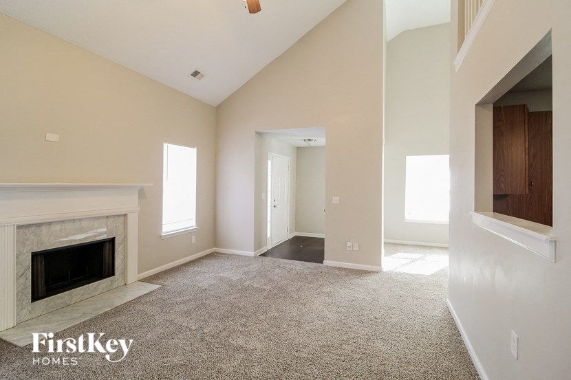 A spacious living room with a fireplace and a carpeted floor.