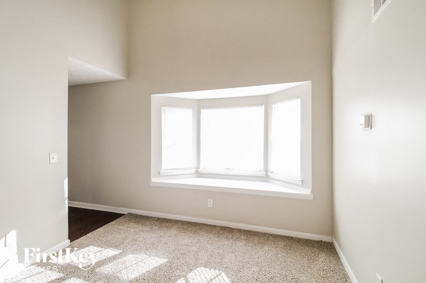 A room with a window and a carpet on the floor.