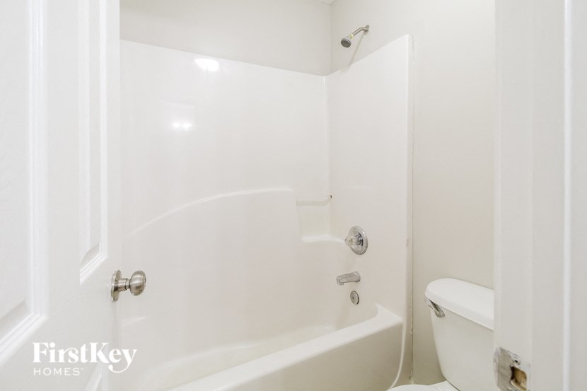 A white bathroom with a tub and toilet.