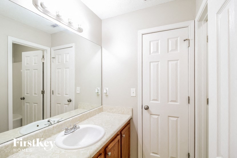 A bathroom with a sink, mirror, and lighting.
