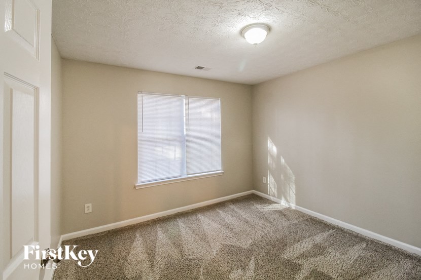 A room with a carpeted floor and a window with blinds.