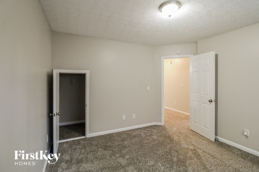 A room with a carpeted floor and two doors, one of which is open.