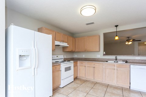 A kitchen with a white refrigerator and wooden cabinets.