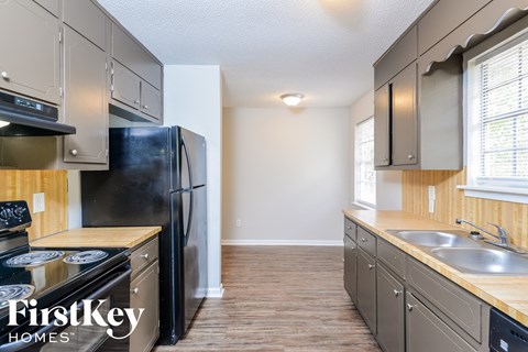 A kitchen with a black refrigerator and wooden cabinets.