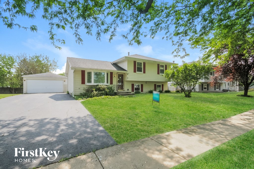 a yellow house with a lawn and a driveway