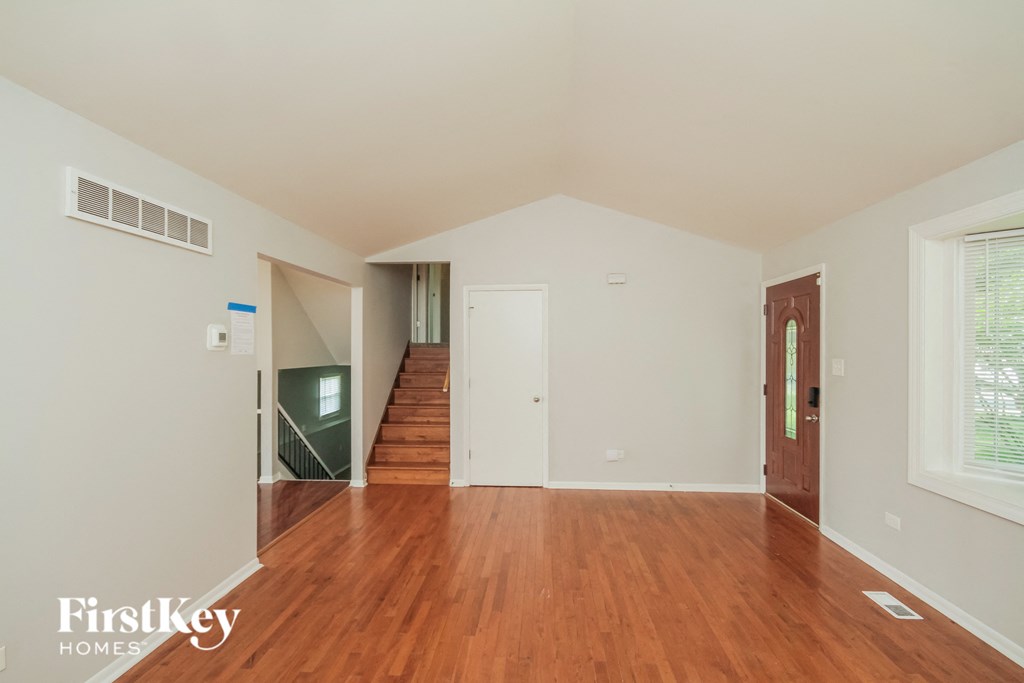 an empty living room with wood flooring and a door to a staircase