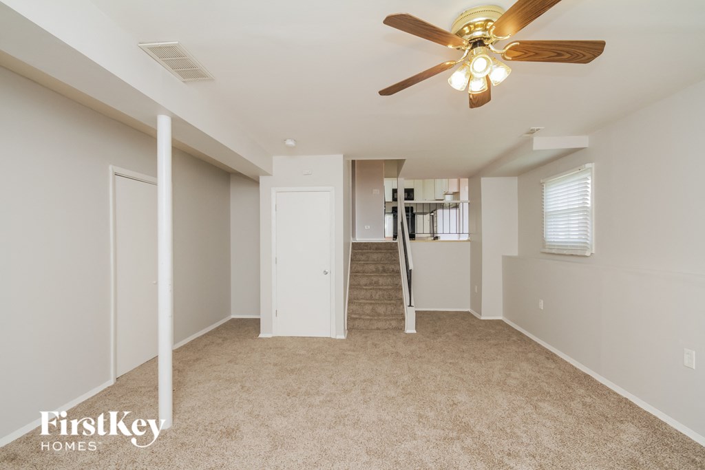 a spacious living room with carpet and a ceiling fan