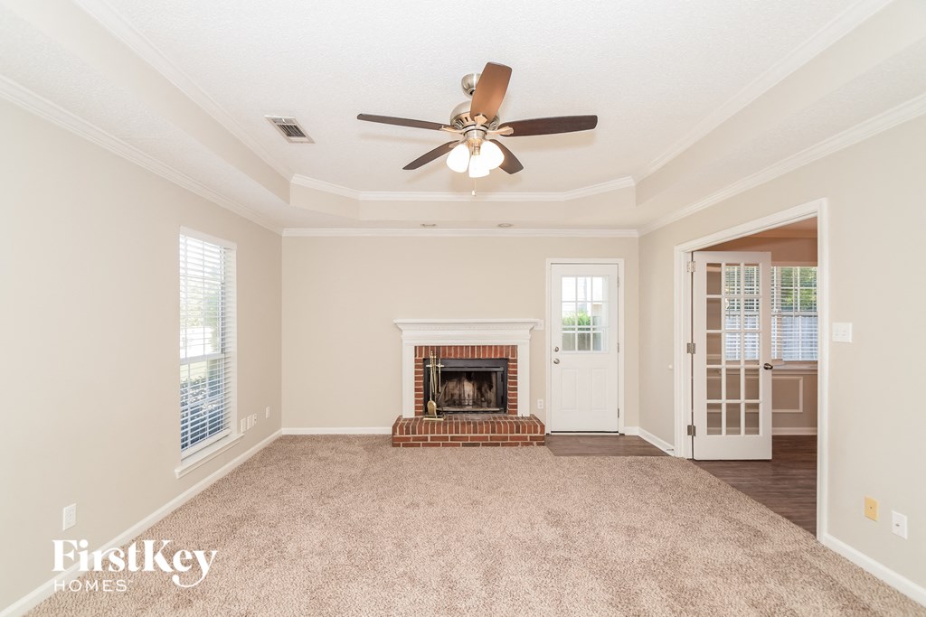 A spacious living room with a fireplace and a ceiling fan.