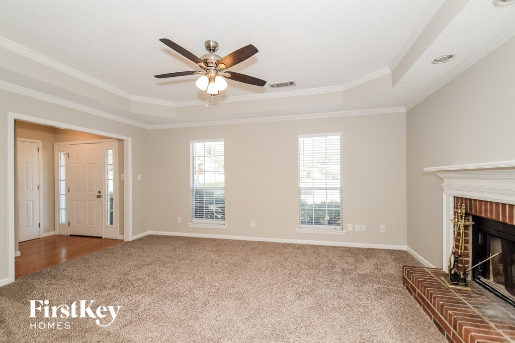 A spacious room with a fireplace and a ceiling fan.