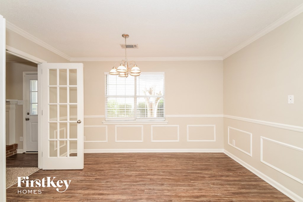 A room with wooden floors and a chandelier hanging from the ceiling.