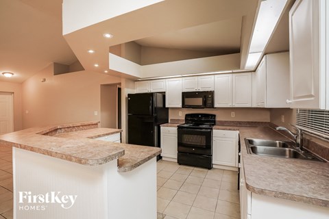 a kitchen with white cabinets and black appliances