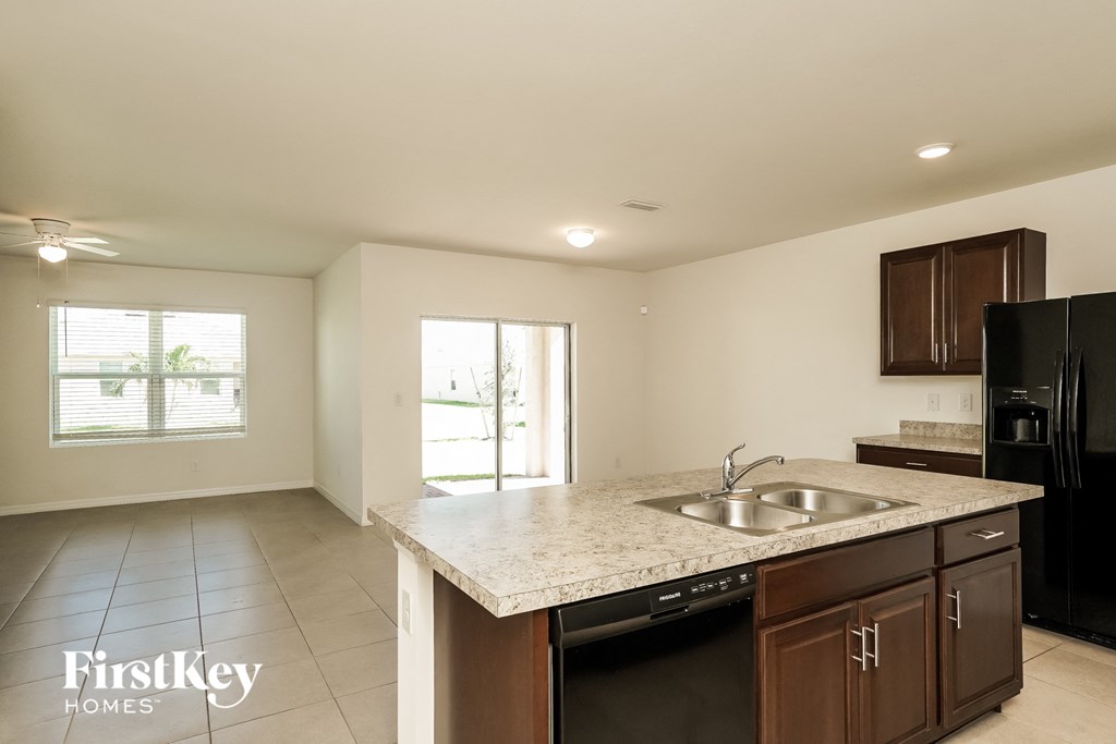 A kitchen with a sink, stove, and cabinets.