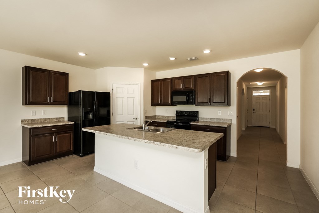 A kitchen with a white island and dark brown cabinets.