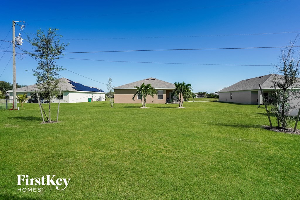 A grassy area with a house and trees in the background.