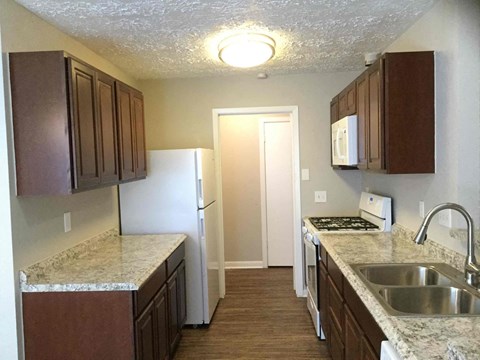 A kitchen with brown cabinets and a white fridge.