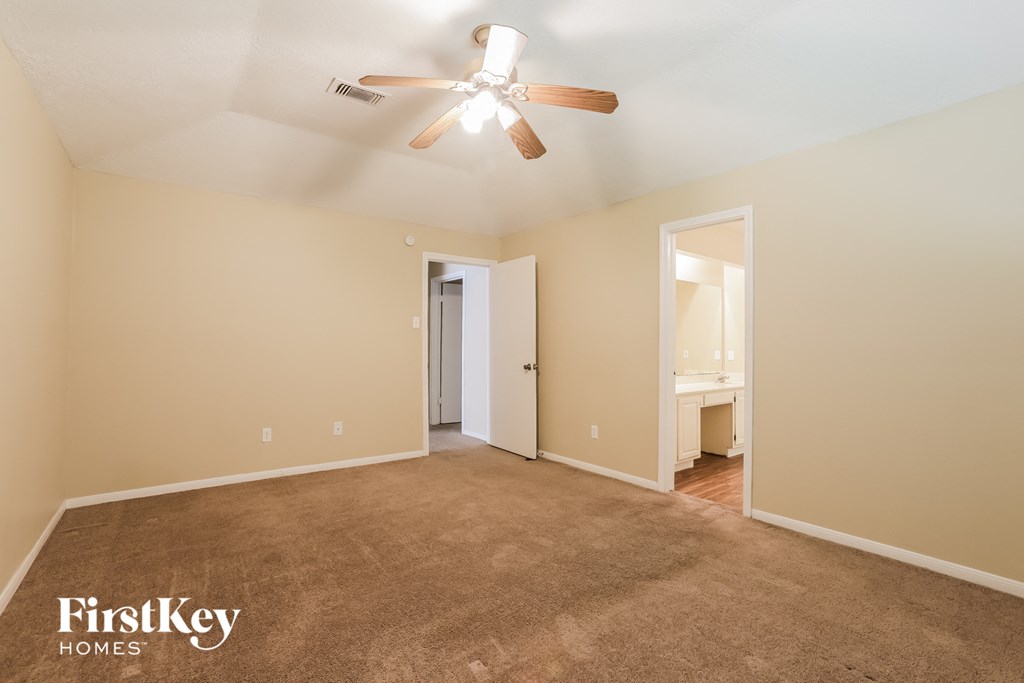a spacious living room with carpet and a ceiling fan