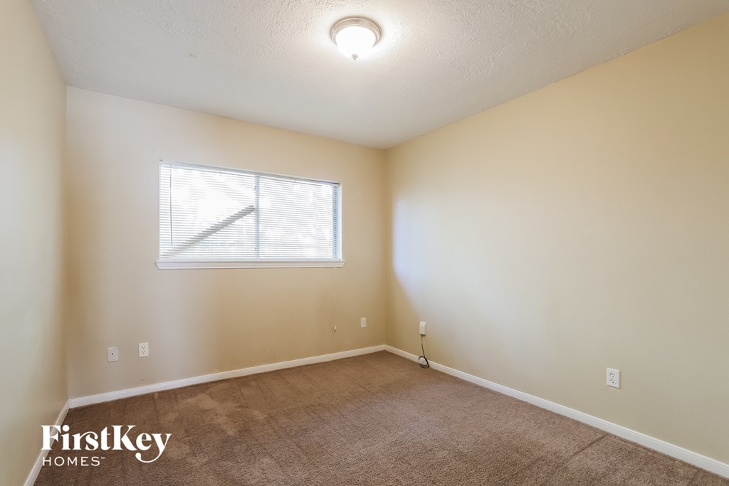 the living room of an empty home with carpet and a window