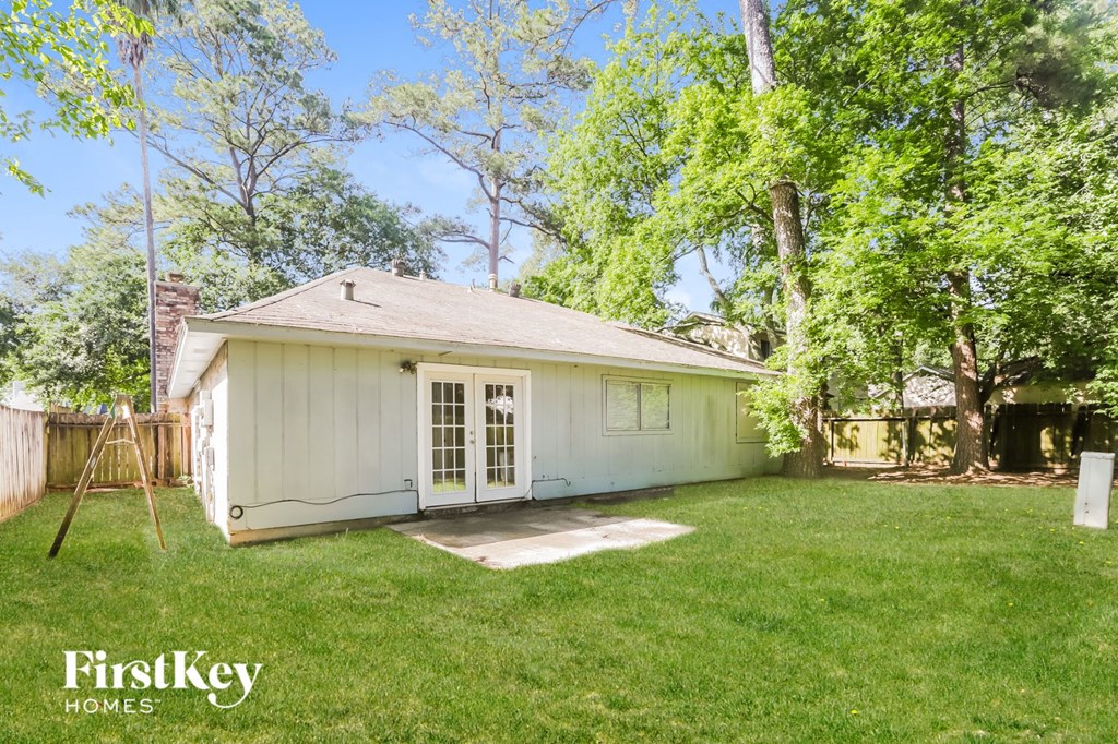 a backyard with a small white house with a lawn and trees