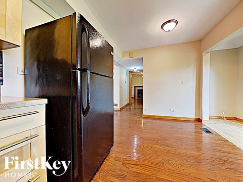A black refrigerator in a kitchen with wooden floors.