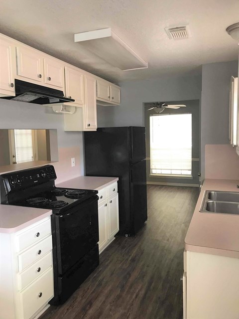 A kitchen with black appliances and white cabinets.
