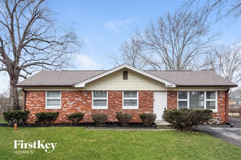 front view of a brick house with a lawn and trees
